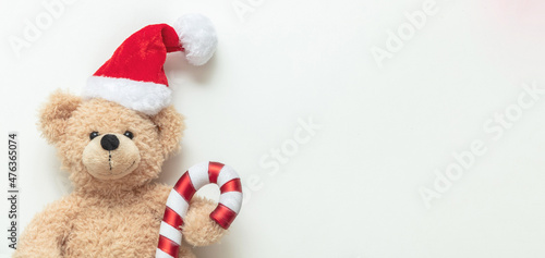Christmas present. Teddy bear wearing a Santa hat on white background, Holiday greeting card. © Rawf8