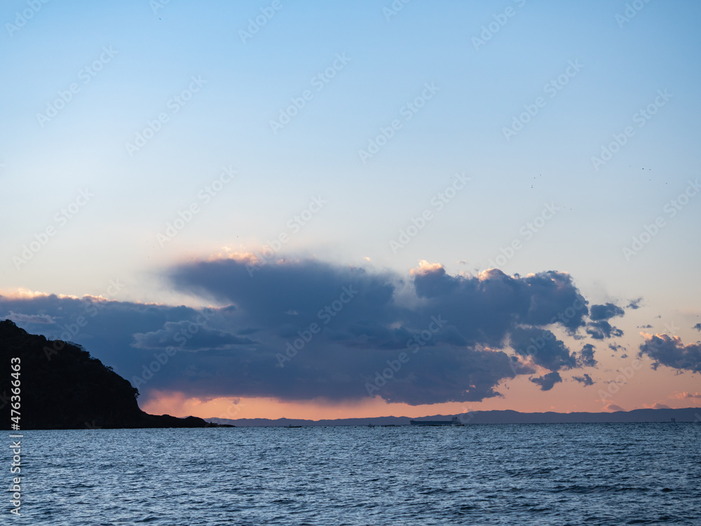 夕焼けの景色。海と雲と山のシルエット。