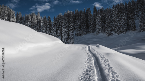 Schitour Spur durch Tiefschnee Winterlandschaft im Sonnenschein.