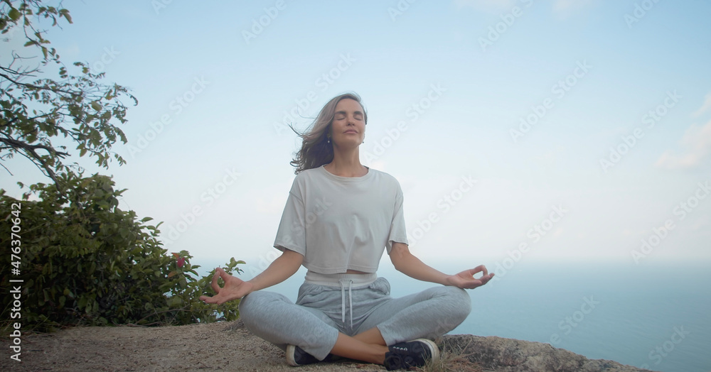 Girl meditate on rock with sea and blue sky view Girl meditate on rock with sea and blue sky view