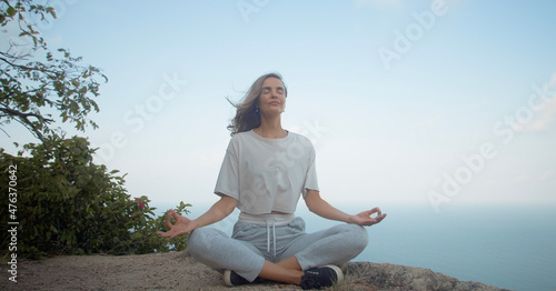 Girl meditate on rock with sea and blue sky view