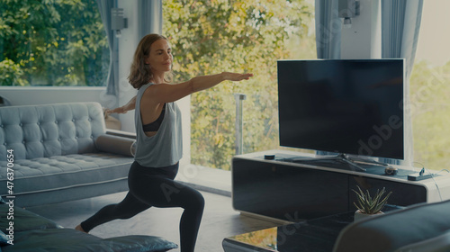 Attractive healthy girl doing yoga in living room.