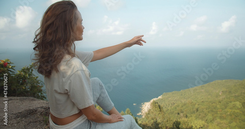 GIrl on peak showing hands on the sea