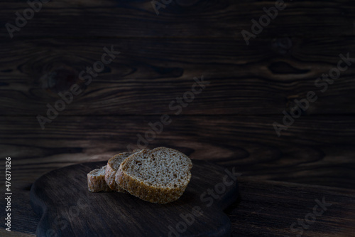 Slices of loaf of rye flour on a dark wooden background. Natural food, bread