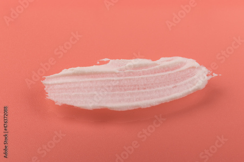 White smear of cosmetic cream isolated on pink background. Creamy foundation texture. Smear of face cream. Texture of cream background