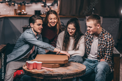 Youth pizza party at home. A young man with a disability with amputated arms in a circle of friends
