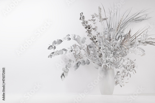 Winter frost white bouquet of dried plant - eucalyptus, reed, fern and flowers in vase on wood table as festive delicate modern home decor for soft light interior, copy space.