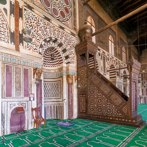 Colorful decorated marble wall with engraved Mihrab - niche - and wooden Minbar - Platform - at Mamluk era public historical mosque of Sultan al Muayyad, Old Cairo, Egypt photo