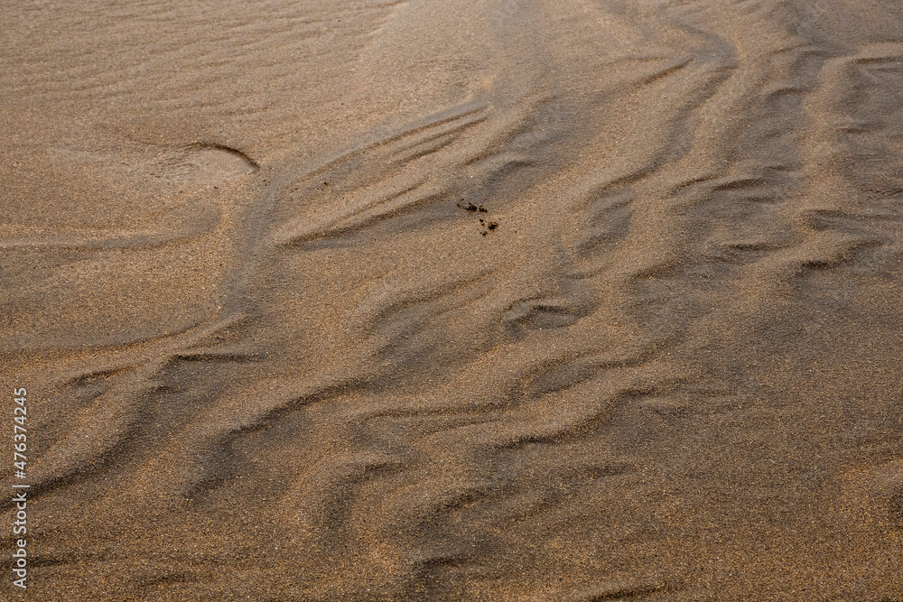 Amazing natural sand pattern made by wind and water on a sandy beach. Unique design for creative purpose. Design background. Random shapes on a dark and light sand surface Amazing natural sand pattern made by wind and water on a sandy beach. Unique design for creative purpose. Design background. Random shapes on a dark and light sand surface