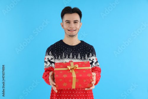 Attractive guy with Christmas gift on blue background