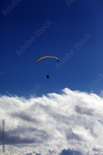 Silhouette of paraglider and blue sky with clouds