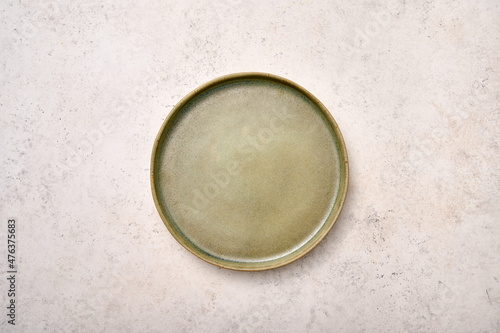 Empty green rustic ceramic plate on light textured marble background, flat lay, copy space