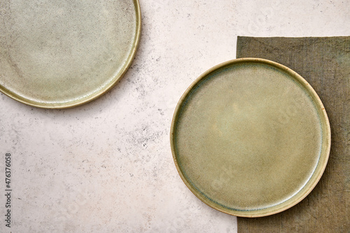 Two green plates with napkin on white textured background. Design concept, copy space