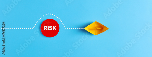 Sailing paper boat comes around the obstacle of risk. Risk avoidance in business photo