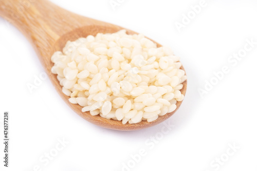 White sesame seeds organic in wooden spoon on white background. Health food concept.
