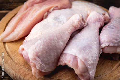 Raw chicken meat: fillet, things and legs on dark wooden background.