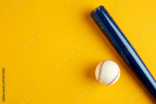 Foto Blue wooden baseball bat and a baseball ball on yellow background