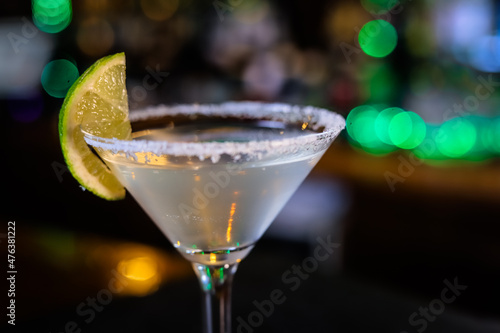 In a funnel-shaped glass with a long stem, the alcoholic cocktail is opaque, opaque, with a slice of lime on the sugared edge of the glass. Filming of the bar menu against the background