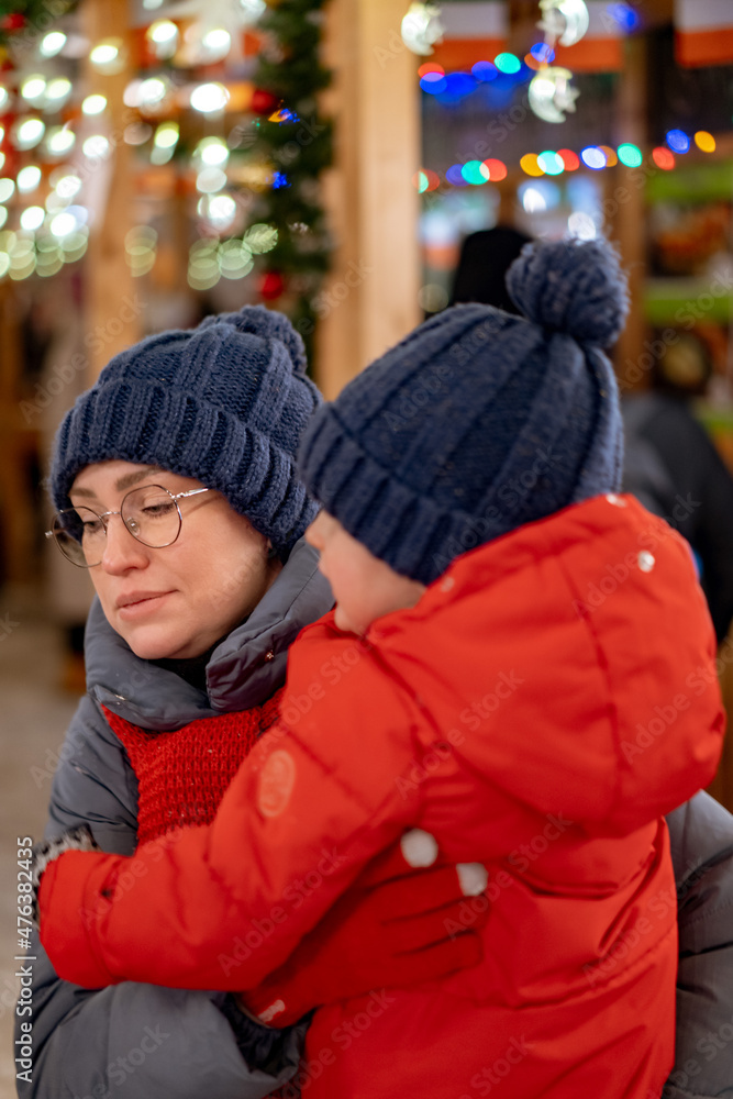 cute baby girl on mother hands outdoors at christmas market cute baby girl on mother hands outdoors at christmas market