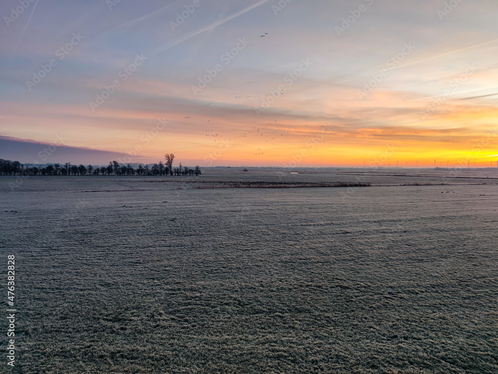 Sonnenaufgang im Winter über einem Feld 