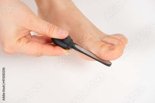 Women s foot on a white background  removal of rough skin on the big toe with a laser file  pedicure