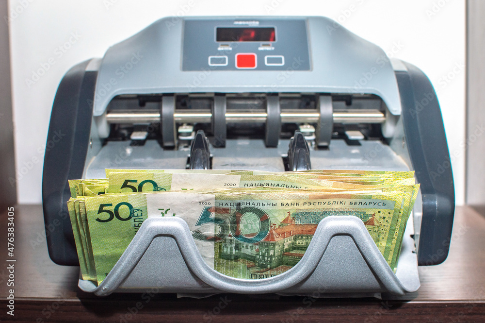 Fototapeta premium Belarusian rubles banknotes in currency Counting Machine. Front view of the shelf. Selective focus.
