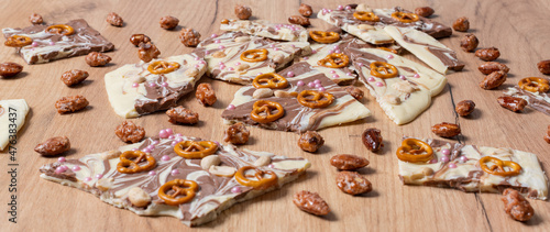 Weiße und braune Schokolade vorbereitet für eine Bruchschokolade dekoriert mit Brezel, Zucker Perlen und Nüssen