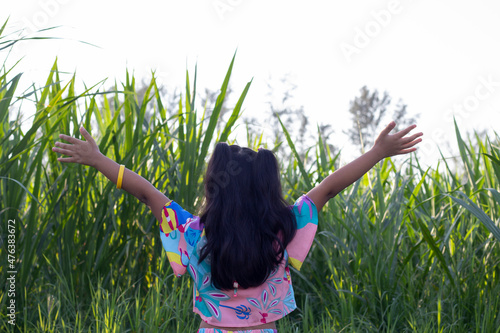 Asian little girl stands and stretches the arms breathe in the fresh air at meadow countryside in the morning.