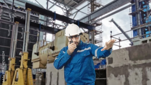 Engineer wearing safety helmet and high visible vest using walkie talkie communication with team inspection installation of heavy duty electric generator using gantry crane lift u on foundation 