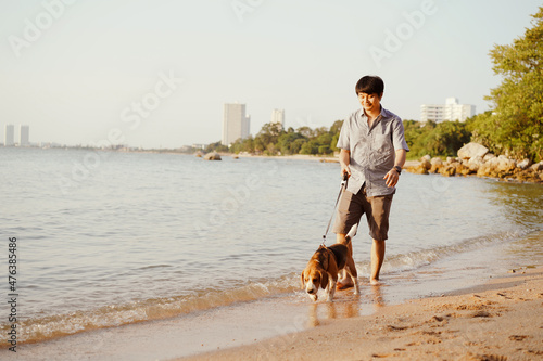 Man with beagle dog on the beach , man lead dog running in everning of summer,Chonburi,Thailand. photo