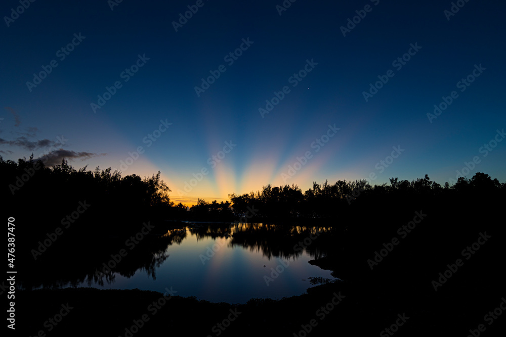 Beautiful and colourful sunset with sun rays reflecting over the water surface at Etang de Saint-Paul, Reunion Island
