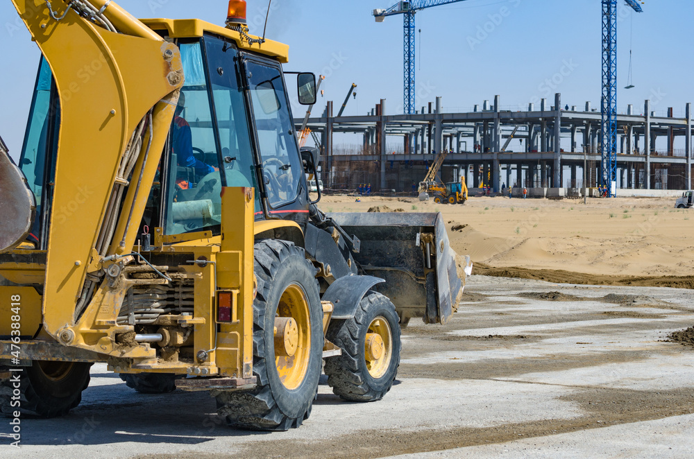 Fototapeta premium Yellow tractor with construction in the background.