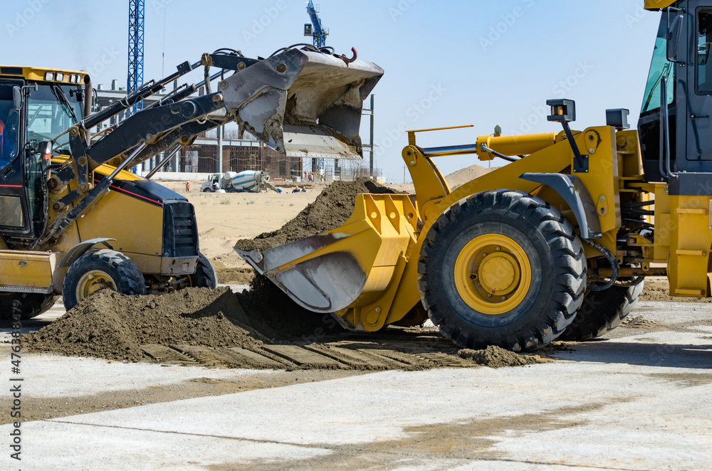 Fototapeta premium Yellow tractors help each other. Construction in the background.