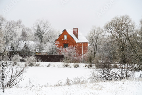A red house on a hill in snowy weather. Heavy snowfall in rural areas. © ru4eek
