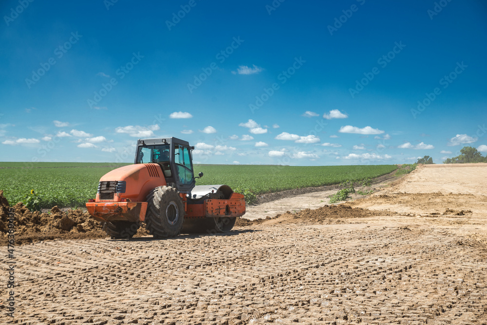 Obraz premium Earthwork during road construction. Orange tractor - Vibrating Roller.