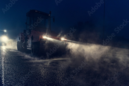 Rolling asphalt at night with headlights. Road construction.