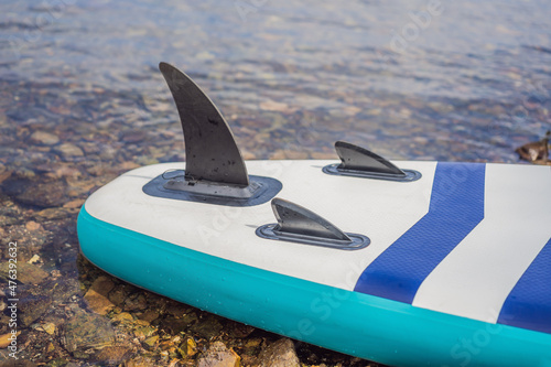 Blue sapboard with paddle and black pump lying on the shore photo