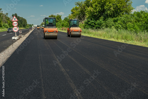 Rollers rolling fresh hot asphalt on the new road. Road construction.