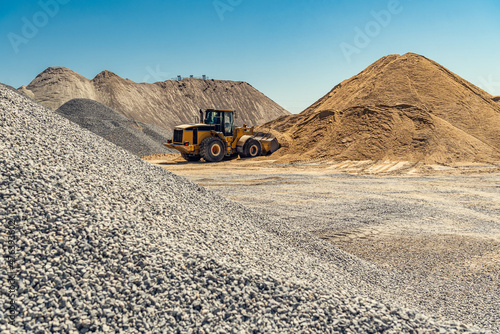 Fototapeta A large powerful loader overloads a sand in a concrete plant.