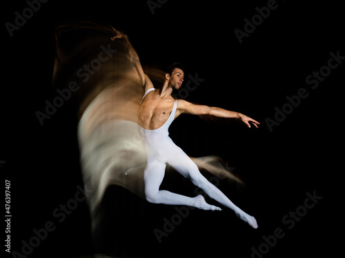 Motion blur ballet dancer jumping on black background