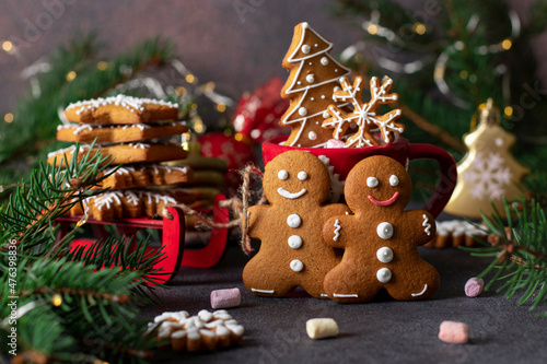 Gingerbread cookies in the form of fabulous gingerbread men, snowflakes and christmas tree. Red sledges and fir tree branches for decoration new year composition
