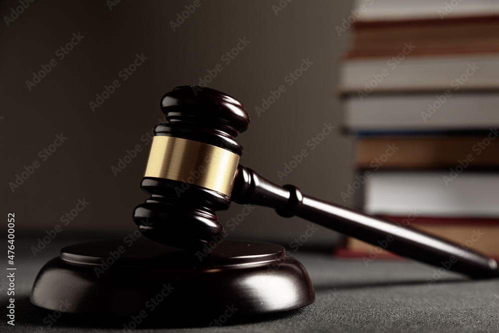 Law and justice. Wooden judge gavel, close-up view against the background of many library books. Law and justice. Wooden judge gavel, close-up view against the background of many library books.