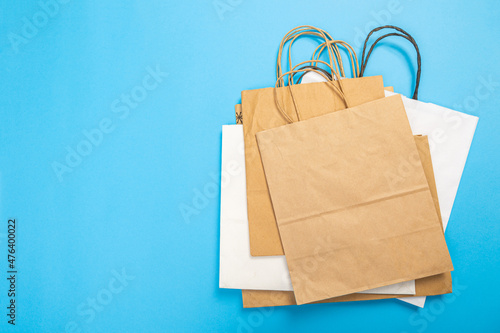 Blank brown paper carrier bag with handles for shopping, facing front on blue background