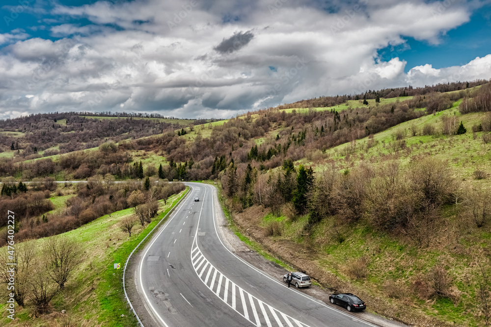 Aerial view of a narrow winding road, through the beautiful wooded Carpathians, amazing spring landscape, outdoor tourist background, Transcarpathia, Ukraine Aerial view of a narrow winding road, through the beautiful wooded Carpathians, amazing spring landscape, outdoor tourist background, Transcarpathia, Ukraine