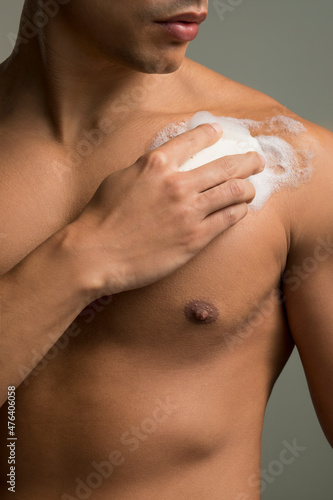 Close-up of man applying soap on chest