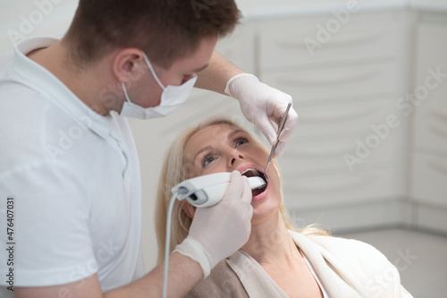 Male dentist doing teeth restoration to a female patient photo