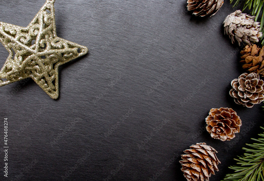 Christmas tree branches, cones and gold shiny star on the black stone plate as background. Holiday concept. Flat lay. Flat lay Christmas tree branches, cones and gold shiny star on the black stone plate as background. Holiday concept. Flat lay. Flat lay