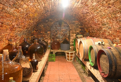 Vintage demijohns in a traditional wine cellar. Demijohn wine bottles and wooden wine barrels