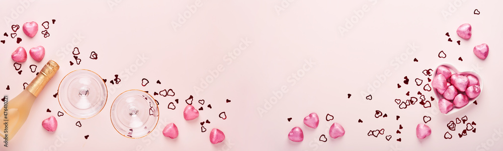 Valentines day greeting card with champagne bottle, tow glasses, chocolate hearts and gift box on pink background. Top view with space for greetings. Greeting card with copy space.