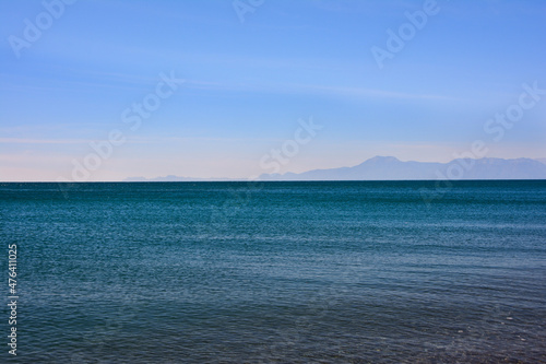 The sea, the horizon line and the blue clear sky. And many mountains in the distance on the horizon